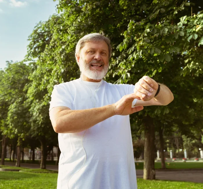 Active senior man checking his fitness watch in a park