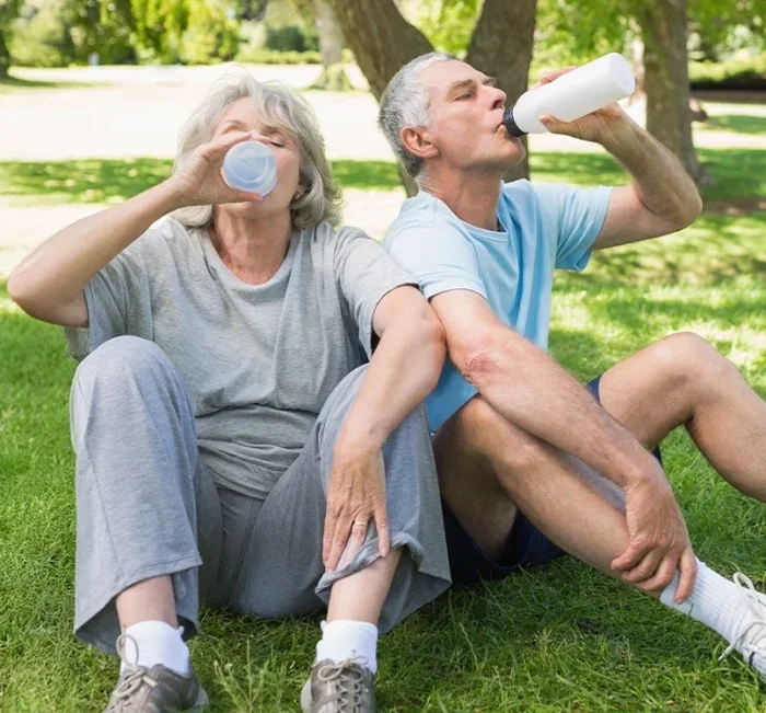 Older couple hydrating after exercise in a park